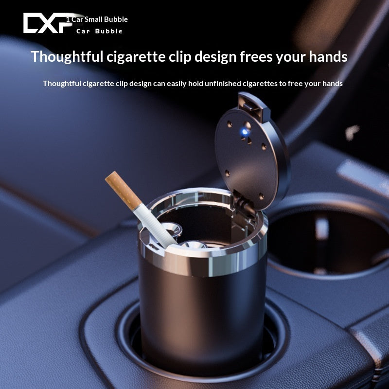 A black cylindrical cigarette holder with an open clip lid, shown in a car cup holder with a cigarette resting inside. White marketing text at the top reads 'DXF Car Small Bubble Car Bubble' and 'Thoughtful cigarette clip design frees your hands.