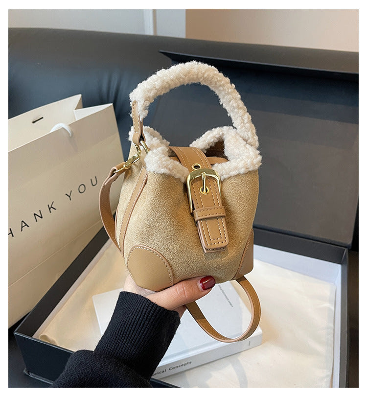 Beige handbag with fur handle held by a person, with a 'THANK YOU' bag in the background.