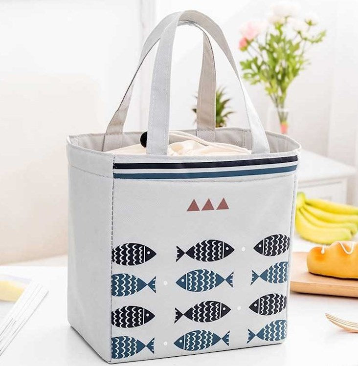 Tote bag with fish pattern on a table with bananas and flowers in the background