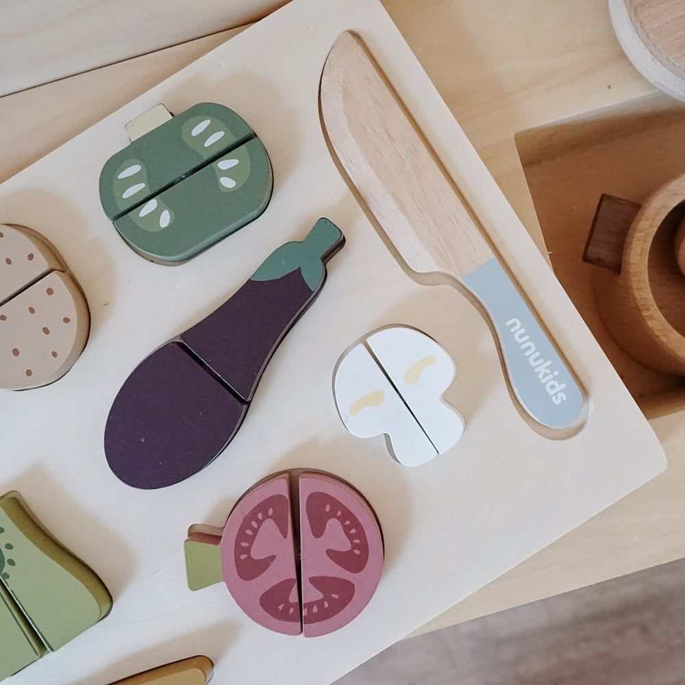 Wooden toy set of vegetables and a knife on a white board, branded 'nurukids'.