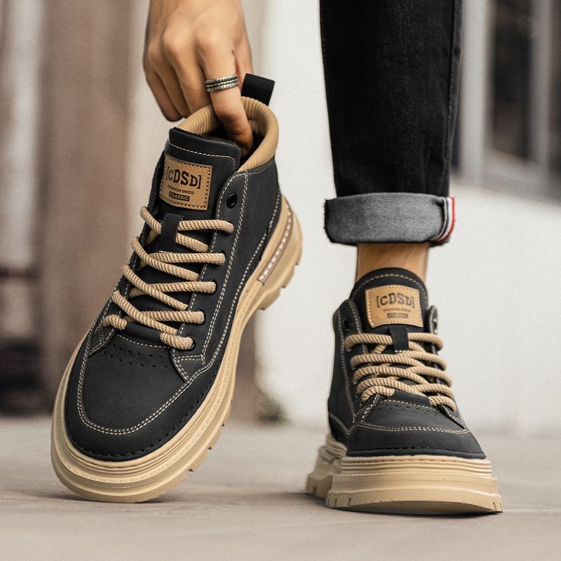 Black and beige boots with 'ICOSDI' branding held by a person wearing black pants.