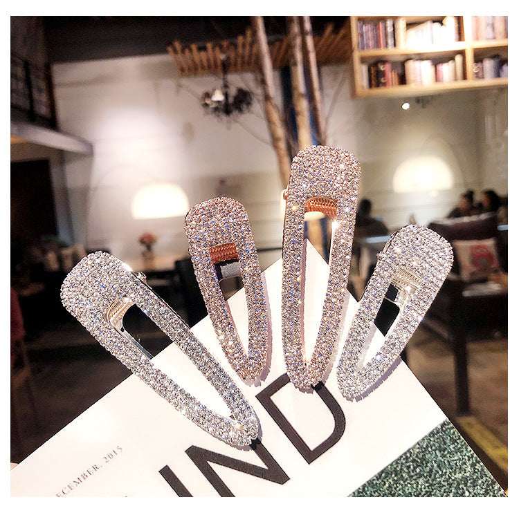 Set of four rhinestone hair clips on a magazine with a blurred indoor background