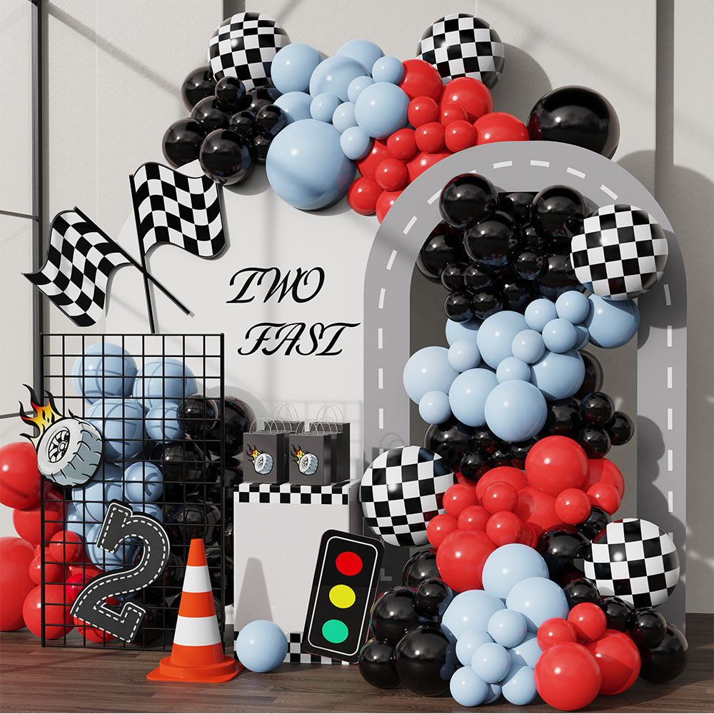 Decorative arch with balloons, checkered flags, and traffic lights for a themed event.