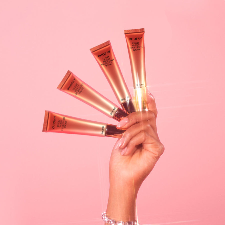 Hand holding multiple skincare tubes against a pink background