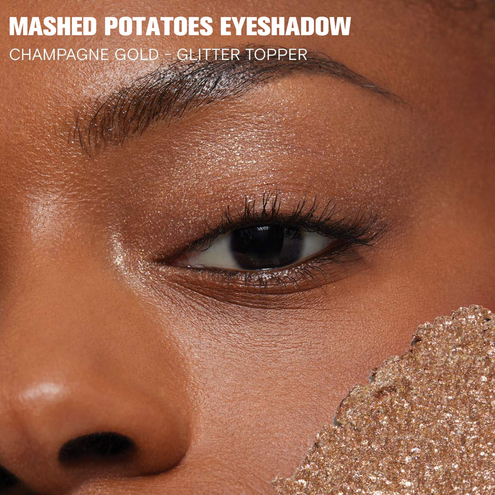 Close-up of eye with glittery eyeshadow labeled 'Mashed Potatoes Eyeshadow' in champagne gold.