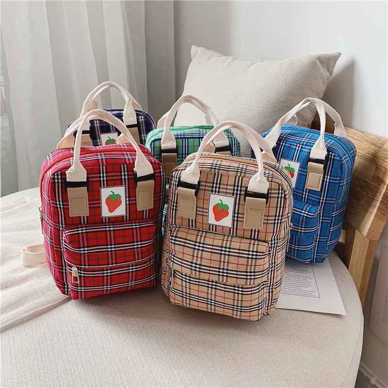 Four plaid patterned bags with strawberry labels on a light surface.