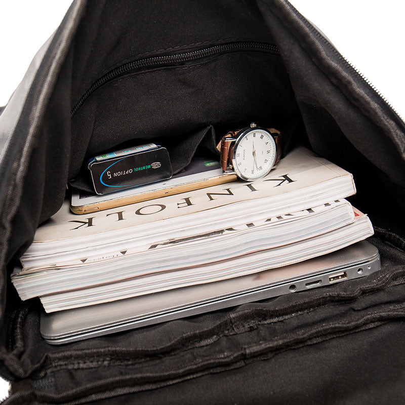 Black backpack with a stack of books, a smartphone, and a watch inside.