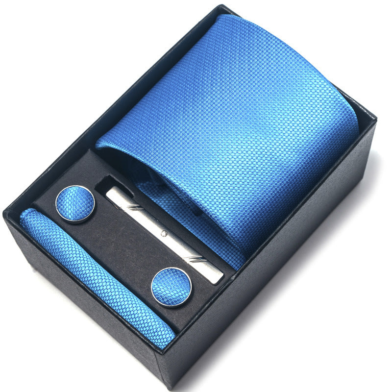 Blue tie set with pocket square, clip, and cufflinks in a black box on a white background