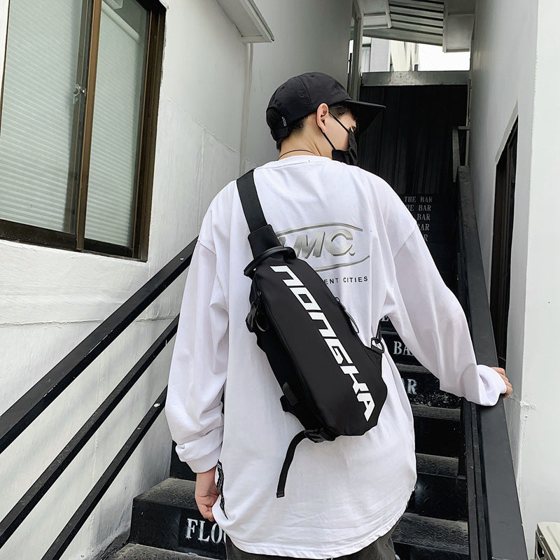 Person wearing a white sweatshirt with a logo and a black backpack, standing on stairs.