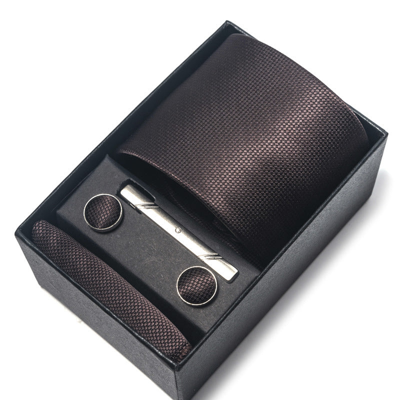 Black textured tie set with tie clip and pocket square in a box on a white background