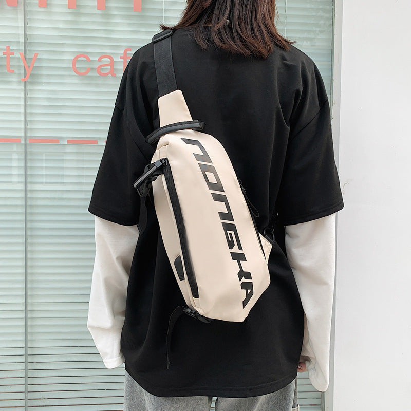 Person wearing a beige backpack with branding, standing in front of a glass door.