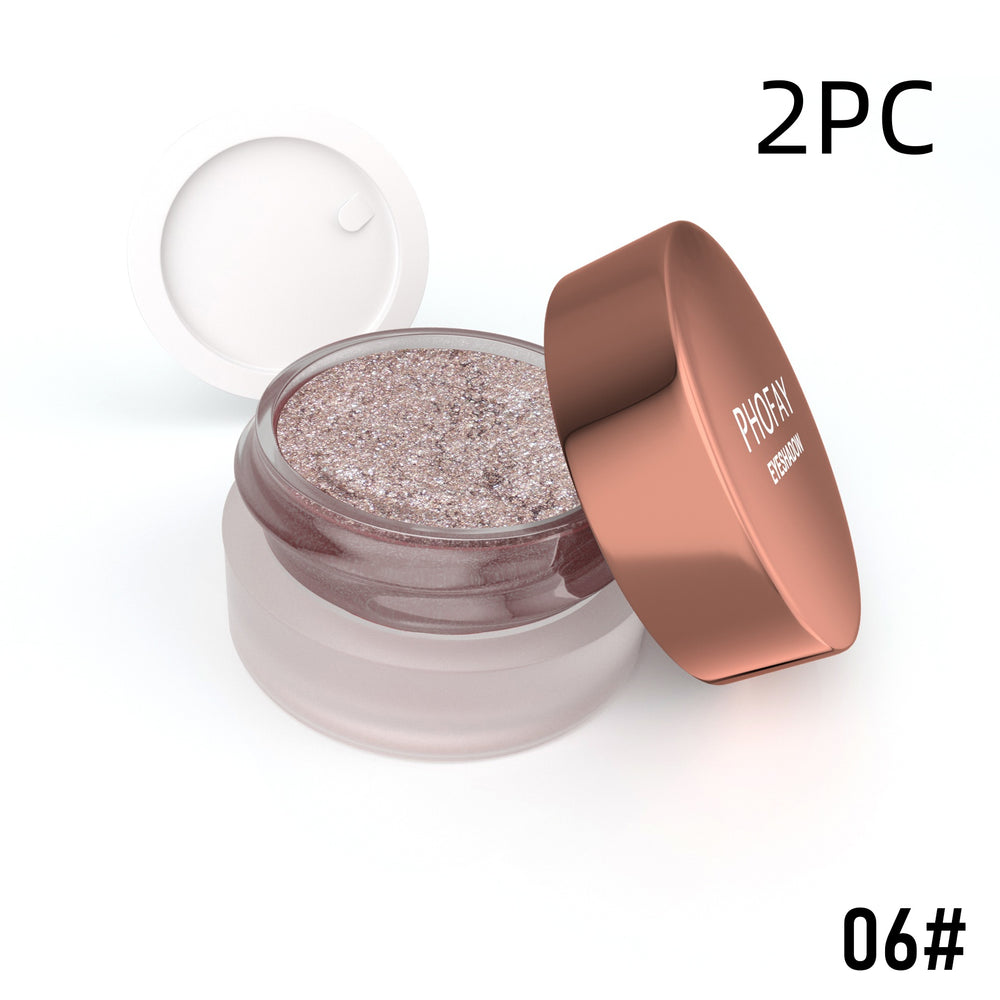 Open jar of glittery makeup with rose gold lid on a white background