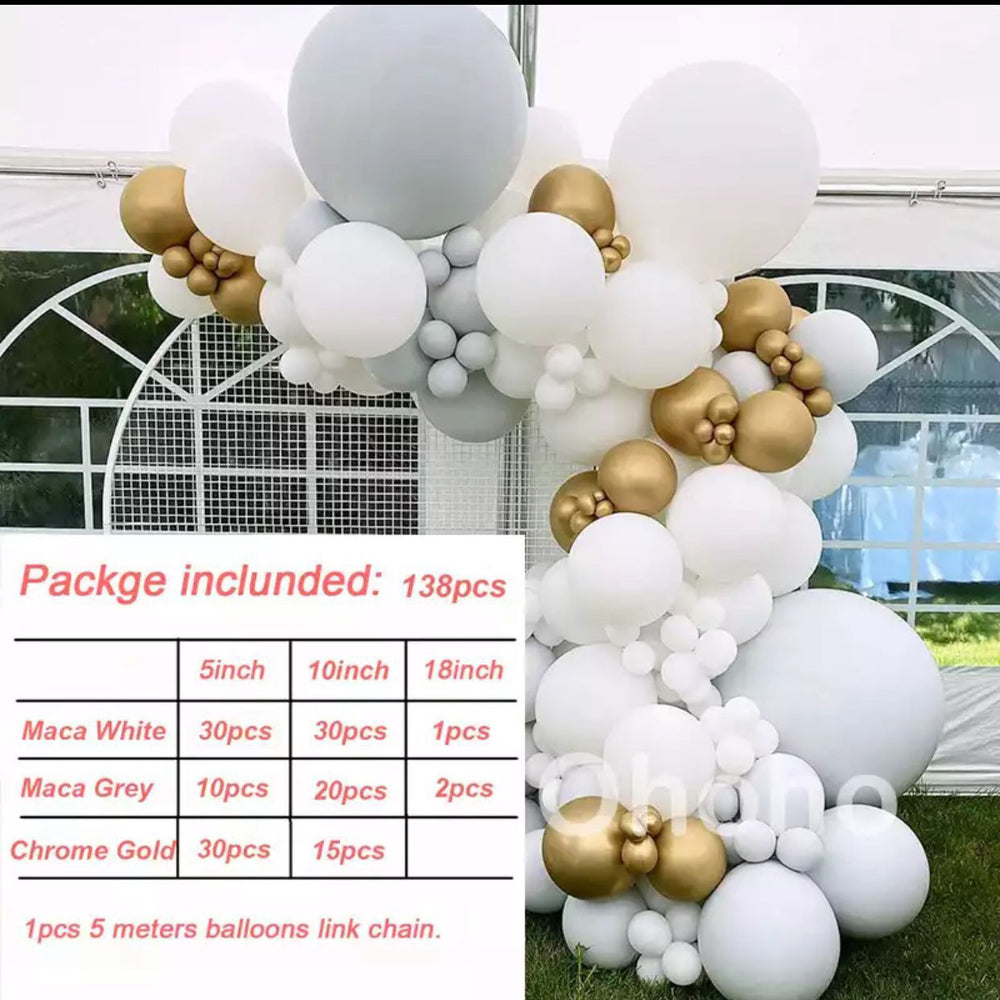 Balloon arch with white, gold, and gray balloons in front of a greenhouse.