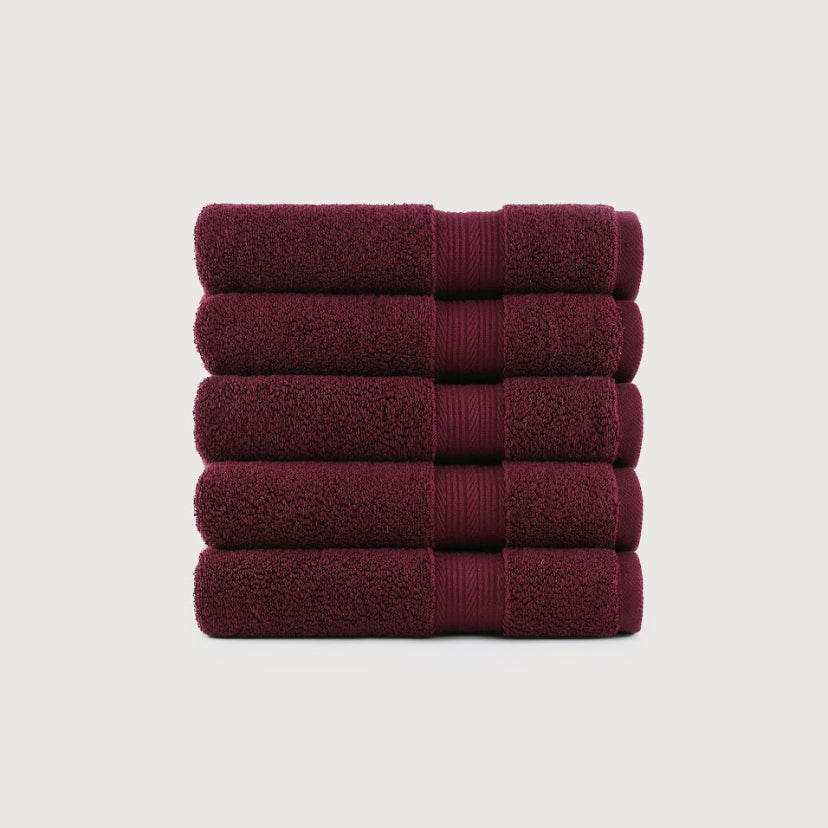 A stack of five folded bath towels in a deep burgundy color, arranged vertically against a light gray background. Pure Cotton Bath Towel Set – Burgundy & Turquoise (74x33cm to 170x95cm)