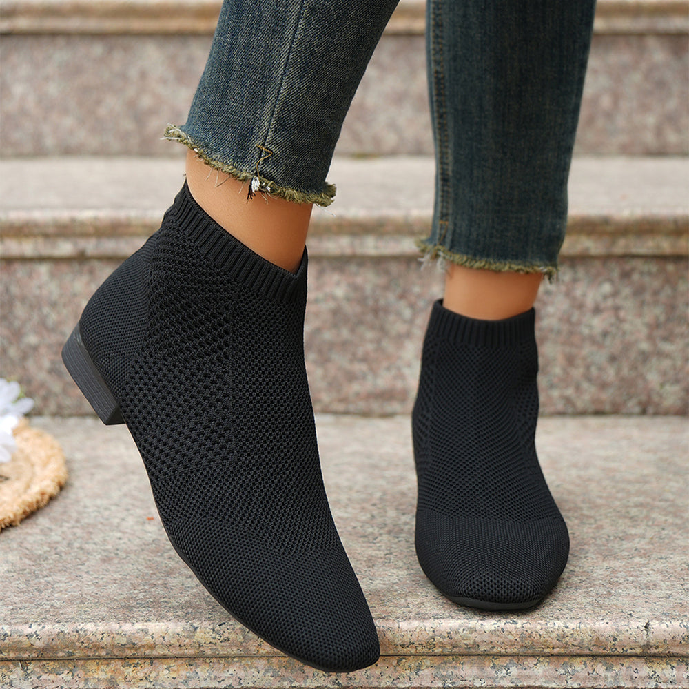 Stivaletti tipo calza neri indossati con jeans su un gradino di pietra
