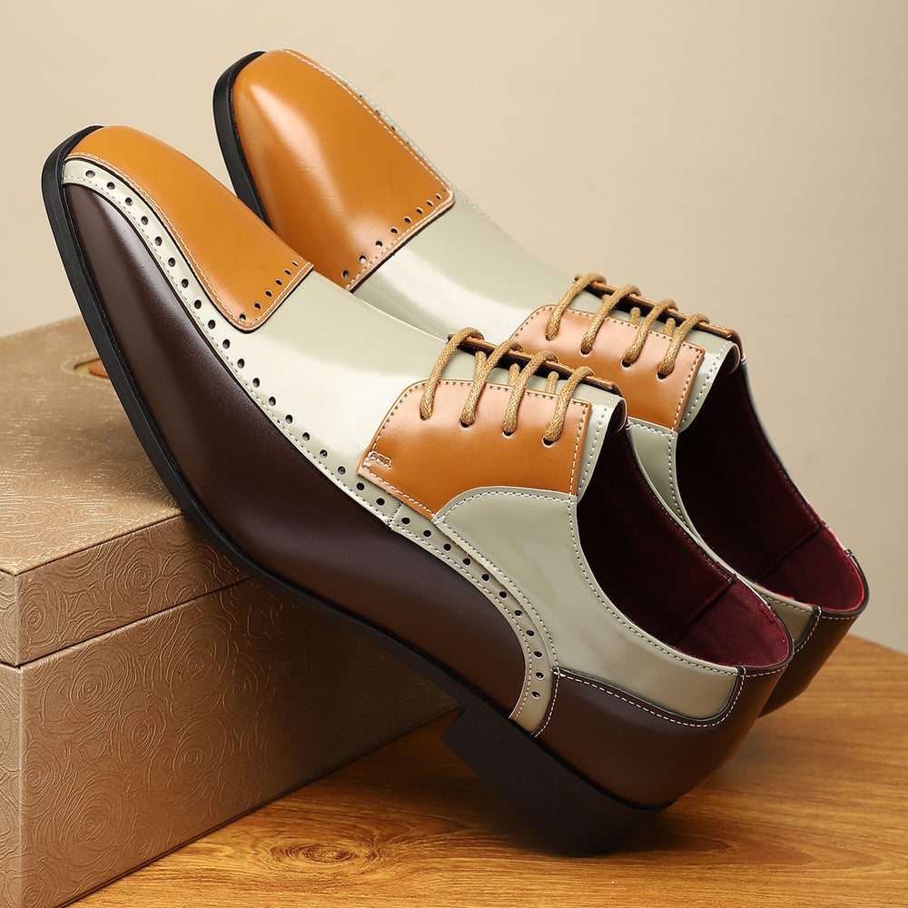 Pair of brown and beige leather shoes on a wooden surface with a beige background