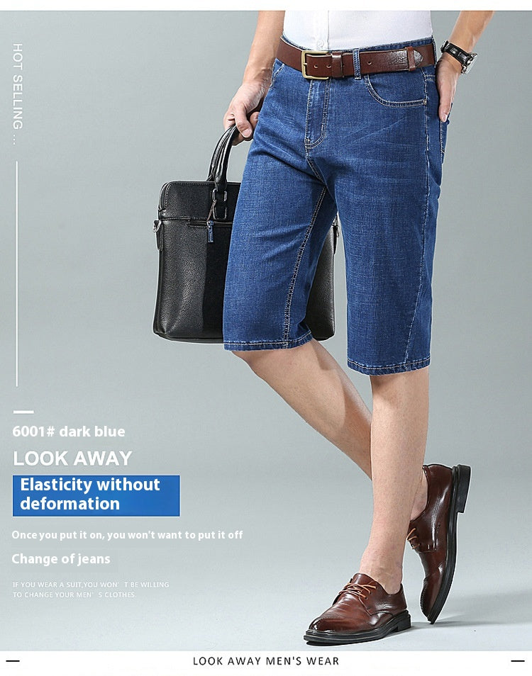 A man modeling dark blue denim knee-length shorts with a brown belt, paired with brown leather dress shoes and holding a black briefcase, set against a light gray studio background with promotional text.