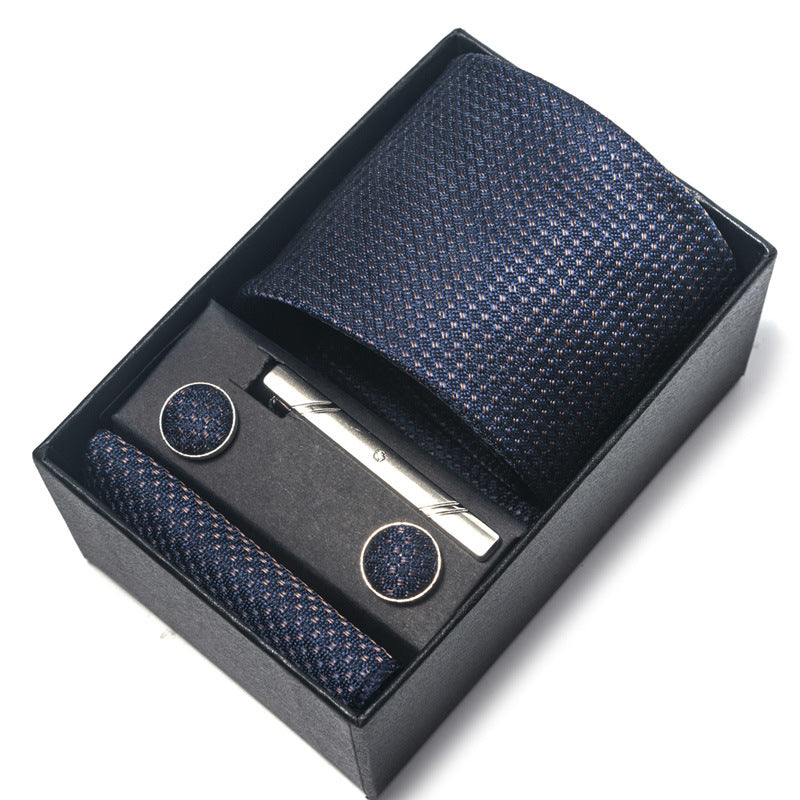 Navy patterned tie set with tie clip and cufflinks in a black box on a white background