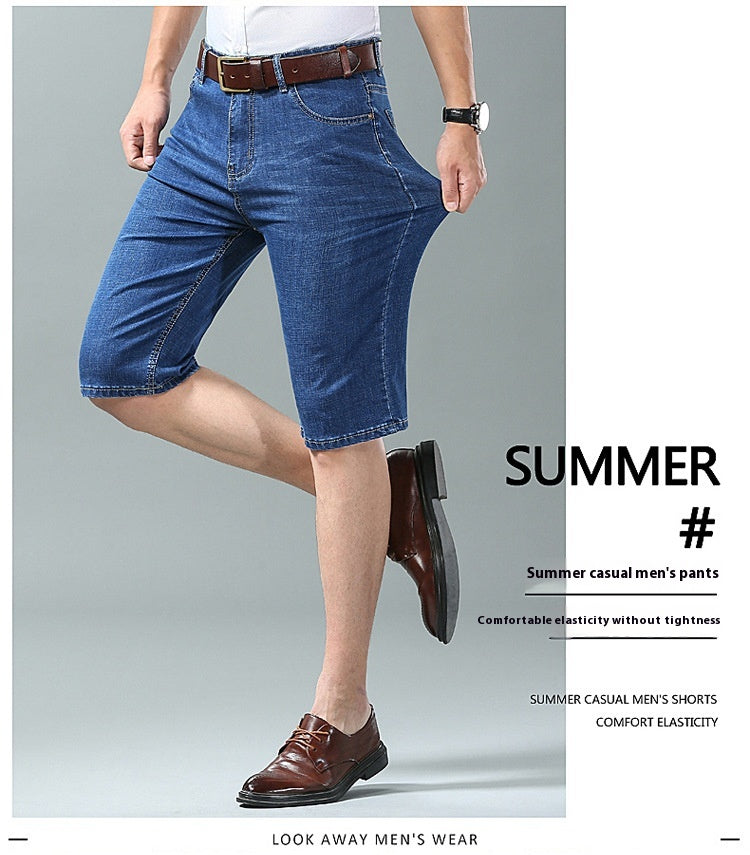 A man modeling blue denim knee-length shorts with a white shirt and brown dress shoes, shown against a light gray studio background with promotional text on the right.