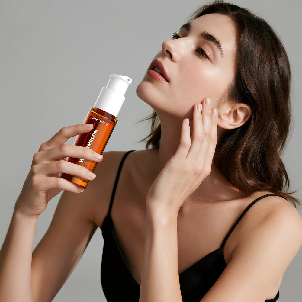 Woman holding a skincare bottle and touching her face against a neutral background