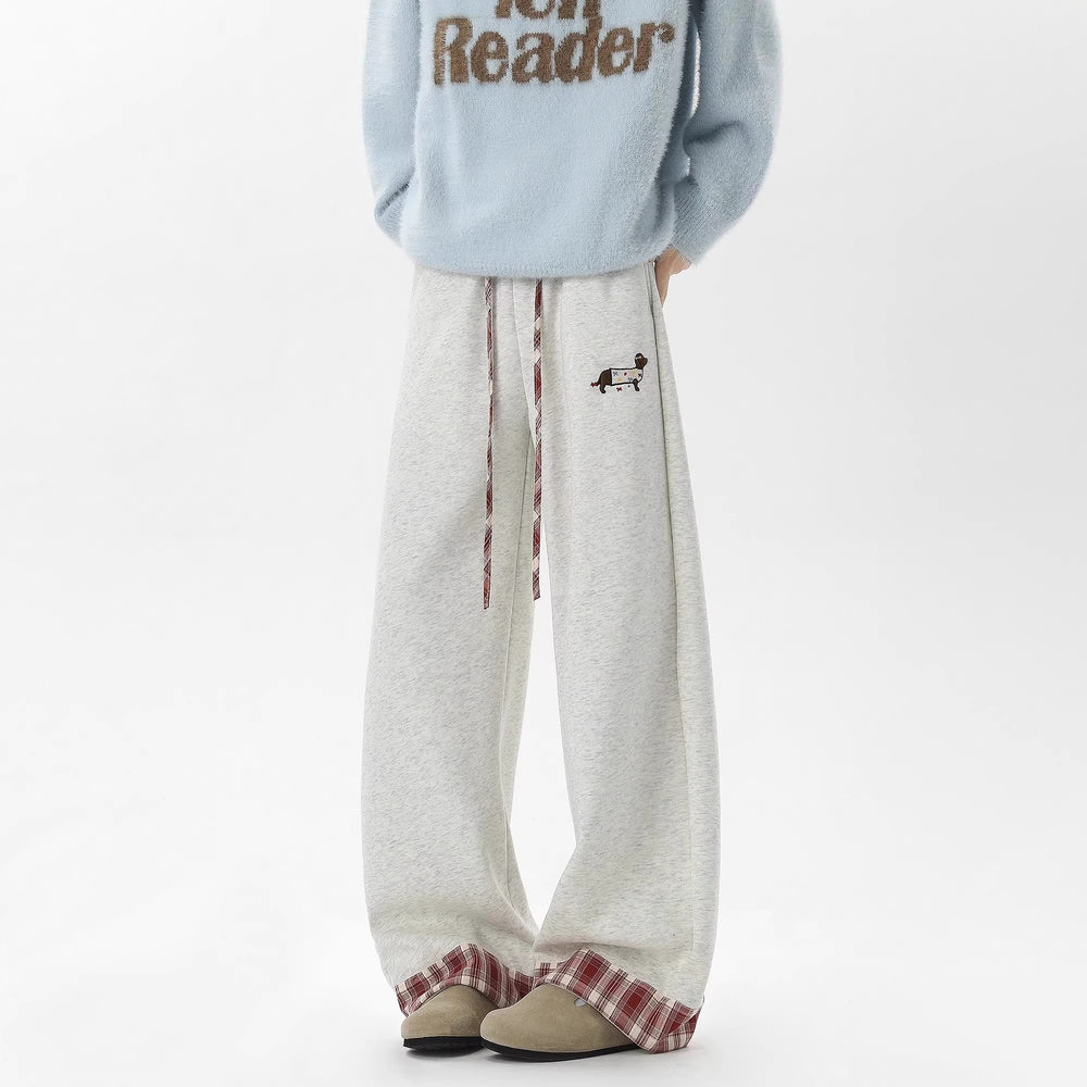 Person wearing light gray sweatpants with plaid cuffs and a blue sweater with text on a white background