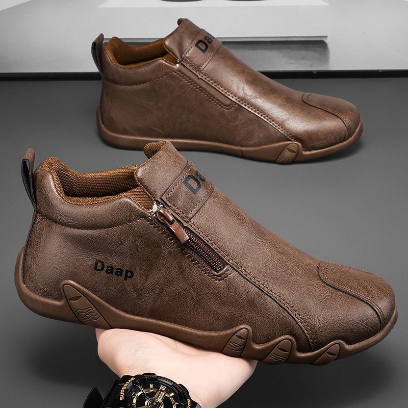 Brown leather shoes with a zipper on a gray background