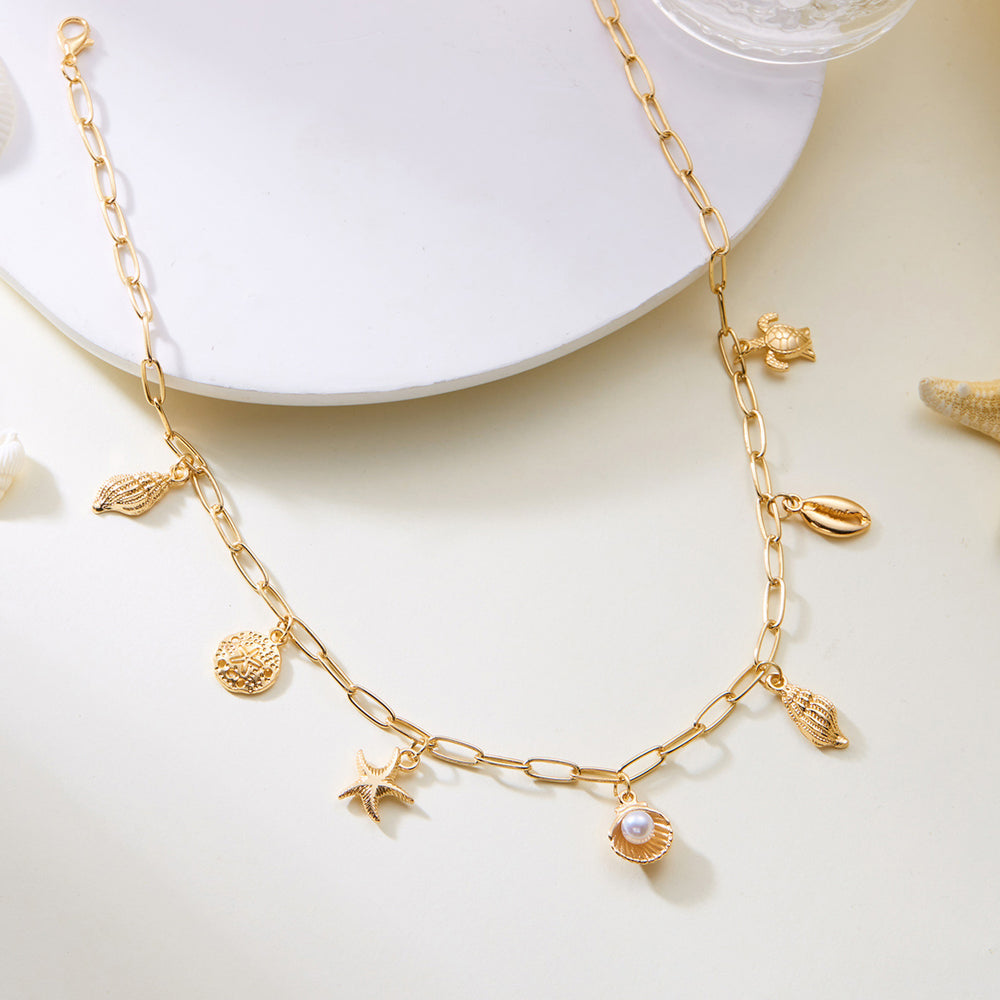 Gold necklace with shell and pearl charms on a white surface