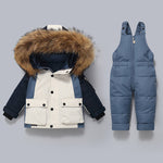 Children's winter jacket with fur hood and blue snow pants on a gray background