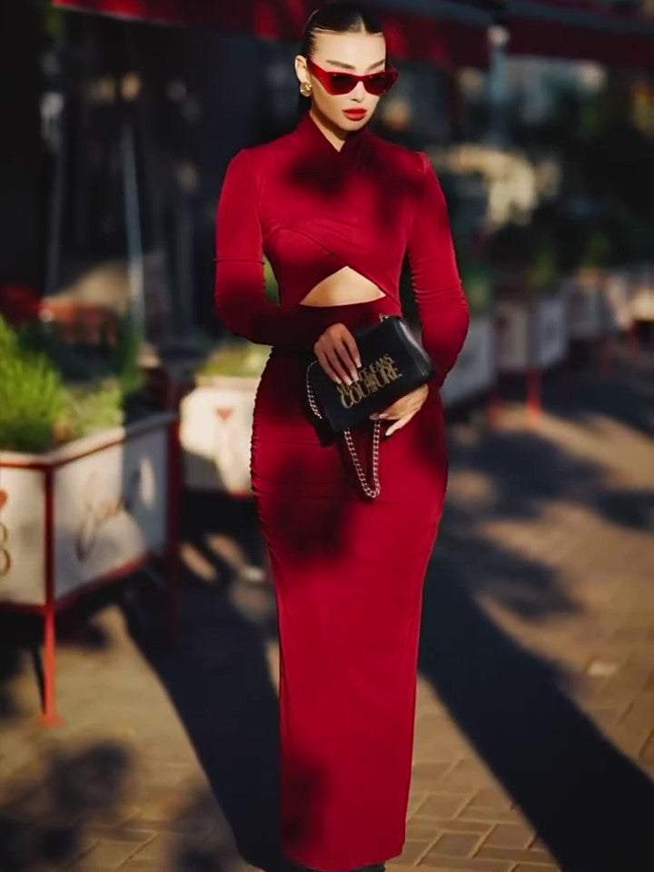 Woman in a red dress holding a black handbag with gold accents outdoors.