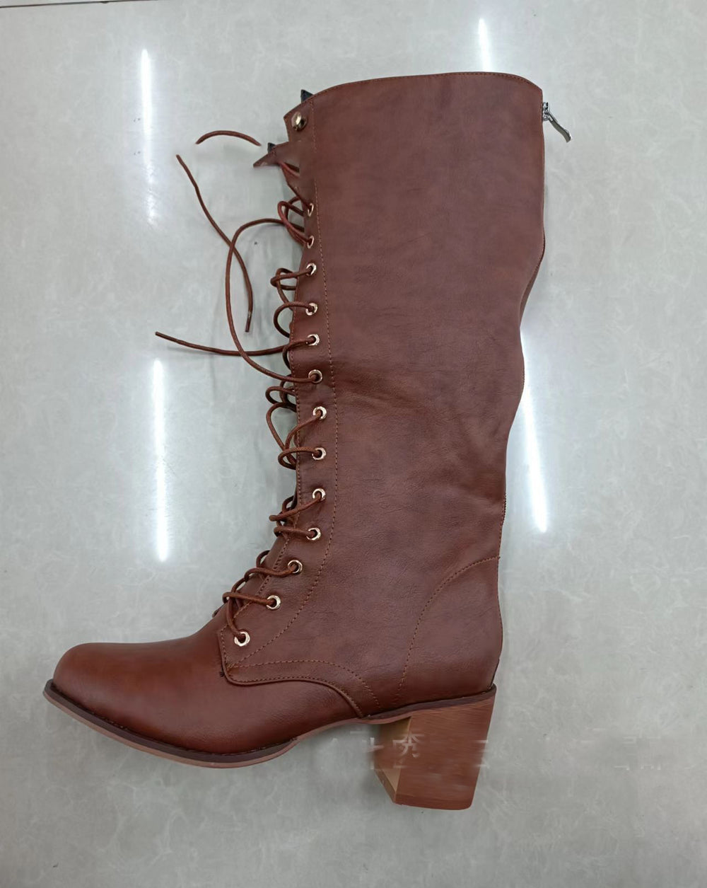 Brown knee-high boot with laces on a light gray background