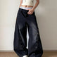 Person wearing black wide-leg jeans with button details on a plain background