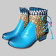 Pair of colorful boots with blue soles on a cardboard surface in an indoor setting.