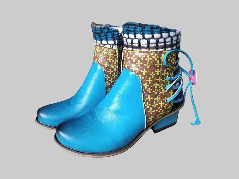 Pair of colorful boots with blue soles on a cardboard surface in an indoor setting.
