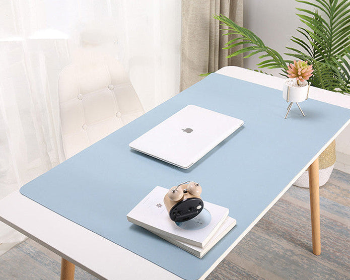Desk with a blue mat, laptop, and decorative items in a home office setting.