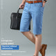 A man modeling light blue denim shorts with a brown belt, paired with brown leather dress shoes and holding a black briefcase, set against a plain gray studio background with promotional text.