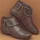 Pair of brown leather ankle boots with a zipper on a beige background