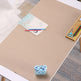 Beige desk pad on a desk with stationery items