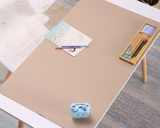 Beige desk pad on a desk with stationery items