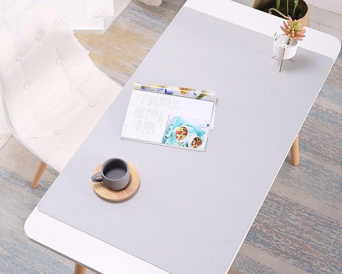 Gray desk with a mug, coaster, and magazine on a wooden floor.