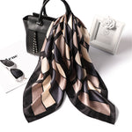 Patterned scarf with black handbag, sunglasses, and white box on a white background
