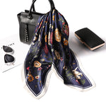 Floral scarf draped over a black handbag with a white background