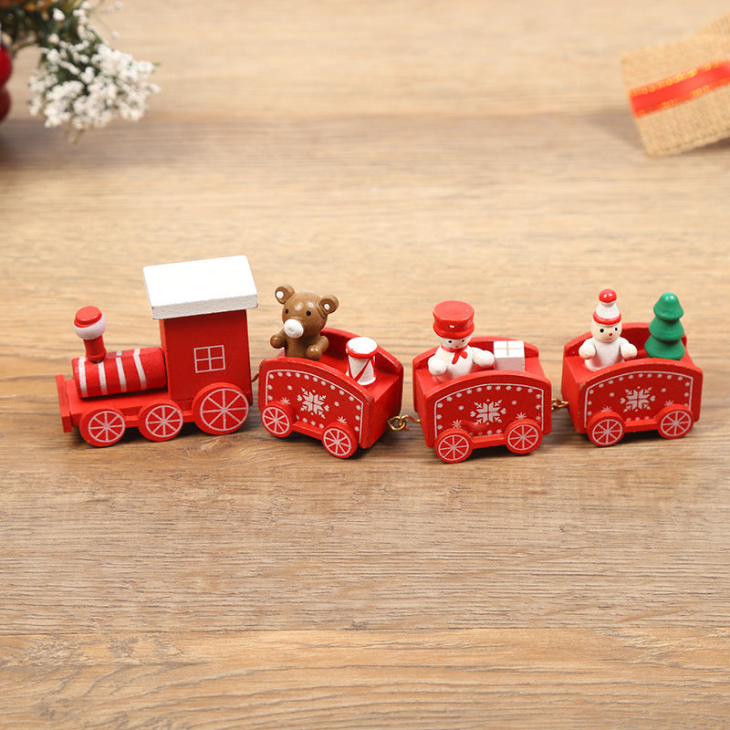 Red toy train with teddy bears and a tree on a wooden surface