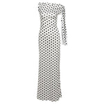 A white off-the-shoulder maxi dress with a black polka dot pattern and a long tie detail on one side, shown against a plain white background.