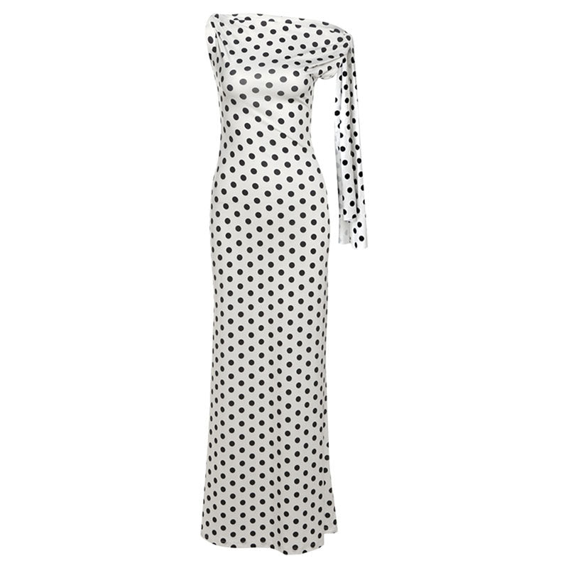 A white off-the-shoulder maxi dress with a black polka dot pattern and a long tie detail on one side, shown against a plain white background.