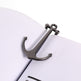 Metallic anchor-shaped object on a white surface