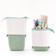 Green and white pencil case with stationery items on a white background