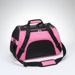 Pink pet carrier with black straps on a brown floor.