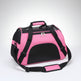 Pink pet carrier with black straps on a brown floor.