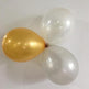 Two gold balloons and two white balloons tied together on a white background