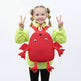 Child wearing a red crab-shaped backpack with a neutral background